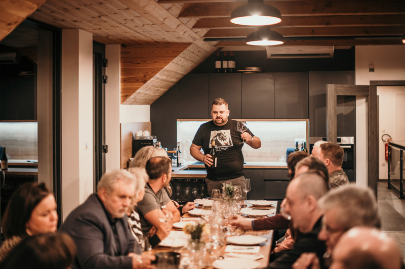 Karel Novotný vede řízenou degustaci pro hosty u dlouhého stolu